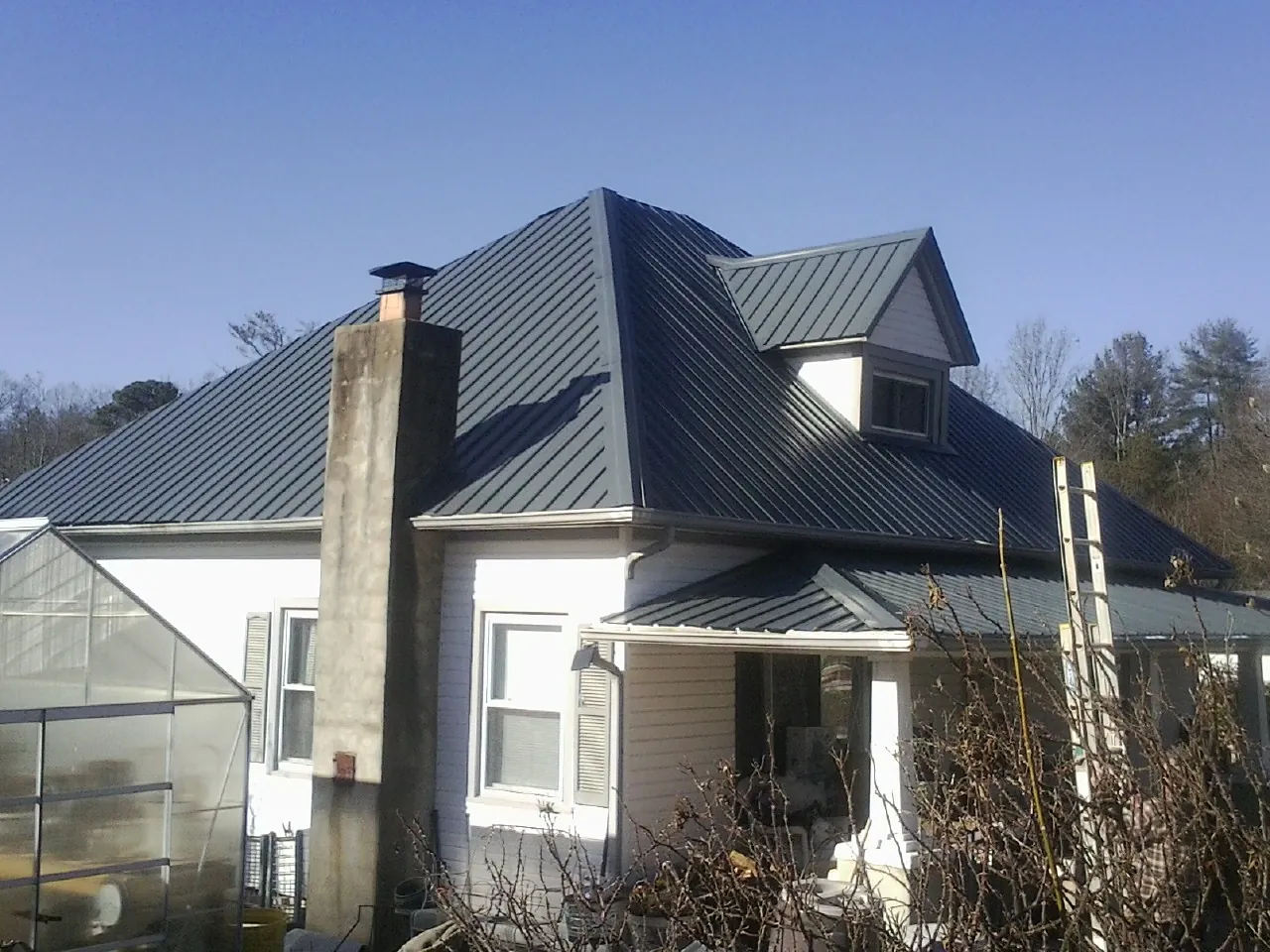 Dark blue standing seam metal roof on a white farmhouse with dormer — Slate & Tile Roof Repair by Roofing Brothers in Greer