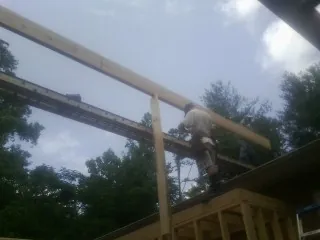 Carpenter setting a ridge beam over a new addition frame — Ice Dam Removal by Roofing Brothers in Greer