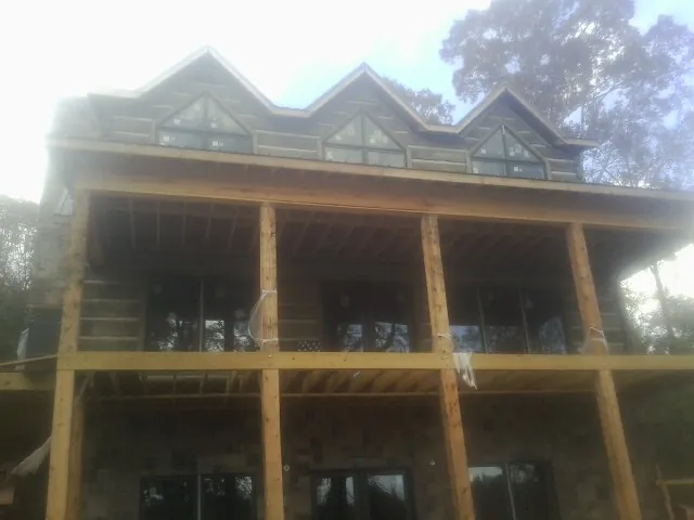 Dormers and porch framing on a large log home under construction — Roof Coating work by our crew in Greer