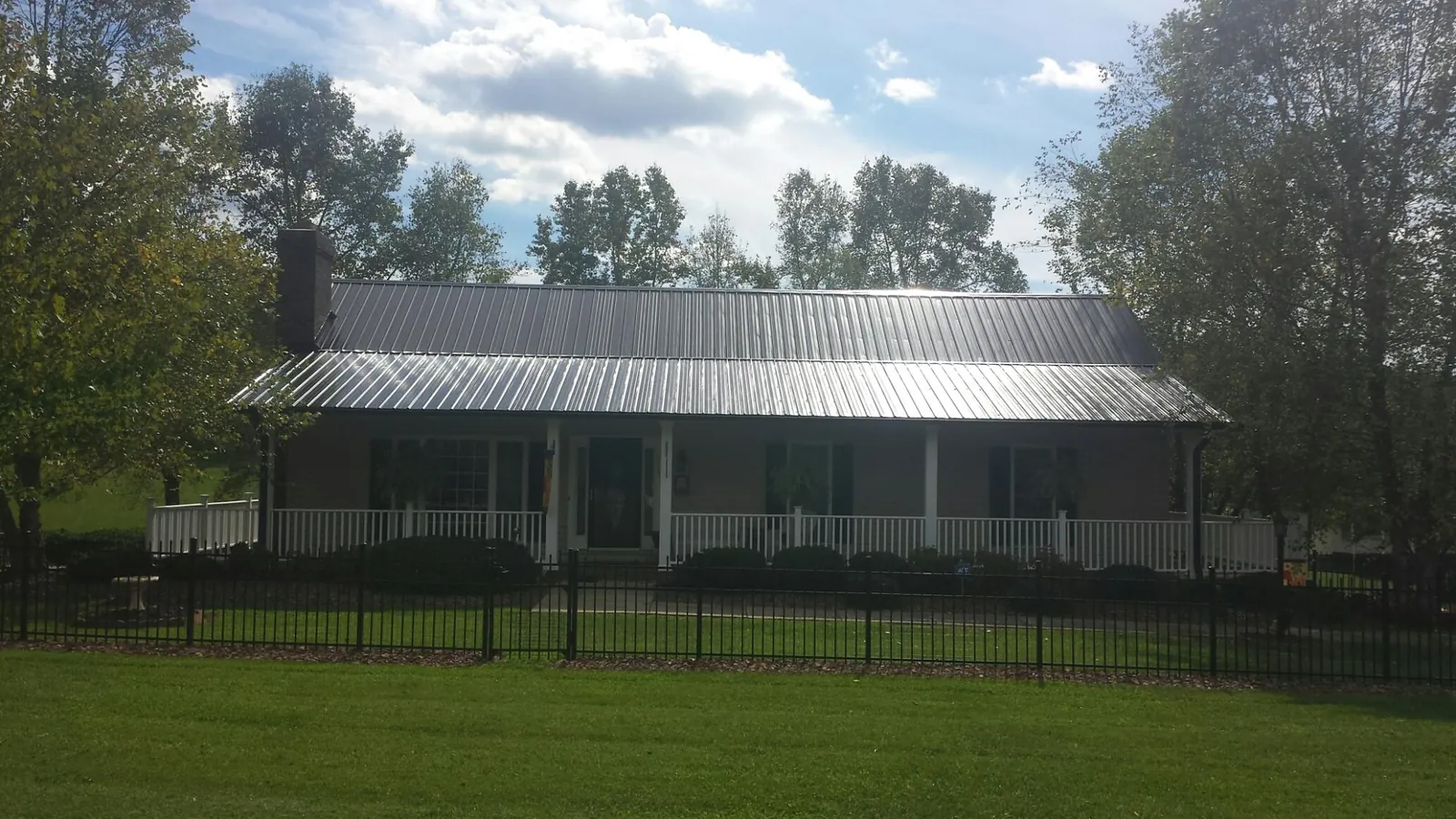 Gray metal roof on a brick ranch with a full width front porch — Gutter Guard Installation work by our crew in Greer