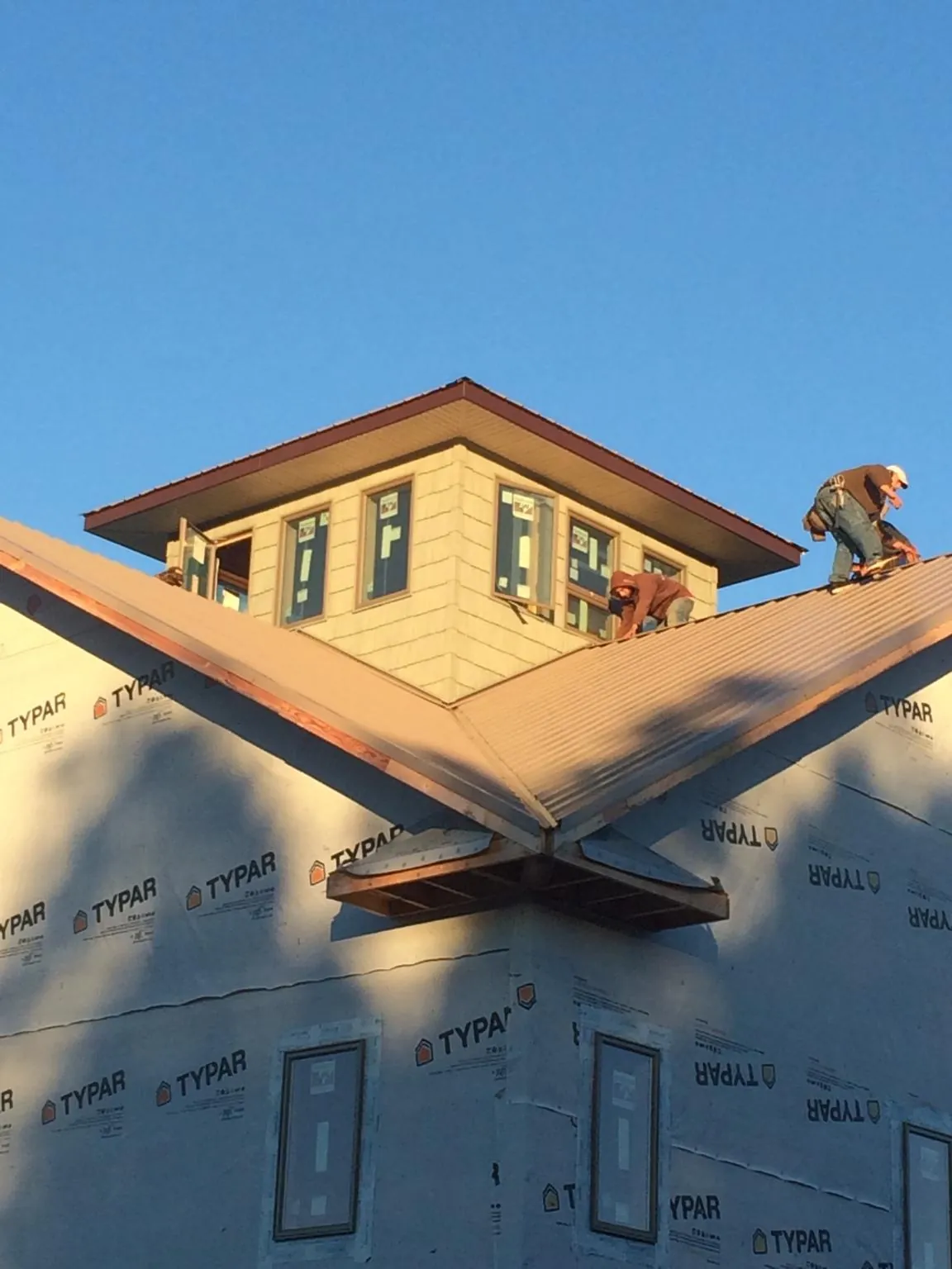 Roofers working around a rooftop cupola on a new metal roof at sunset — Roof Waterproofing in Greer by Roofing Brothers